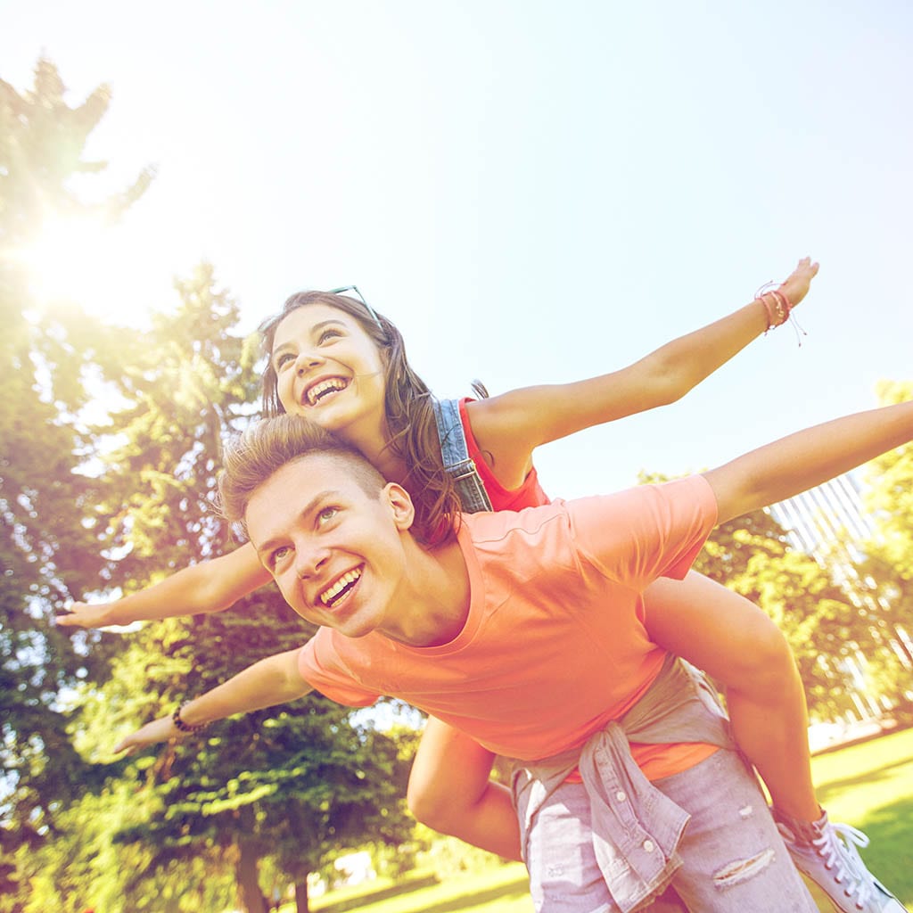 smiling teenage couple having fun at summer park