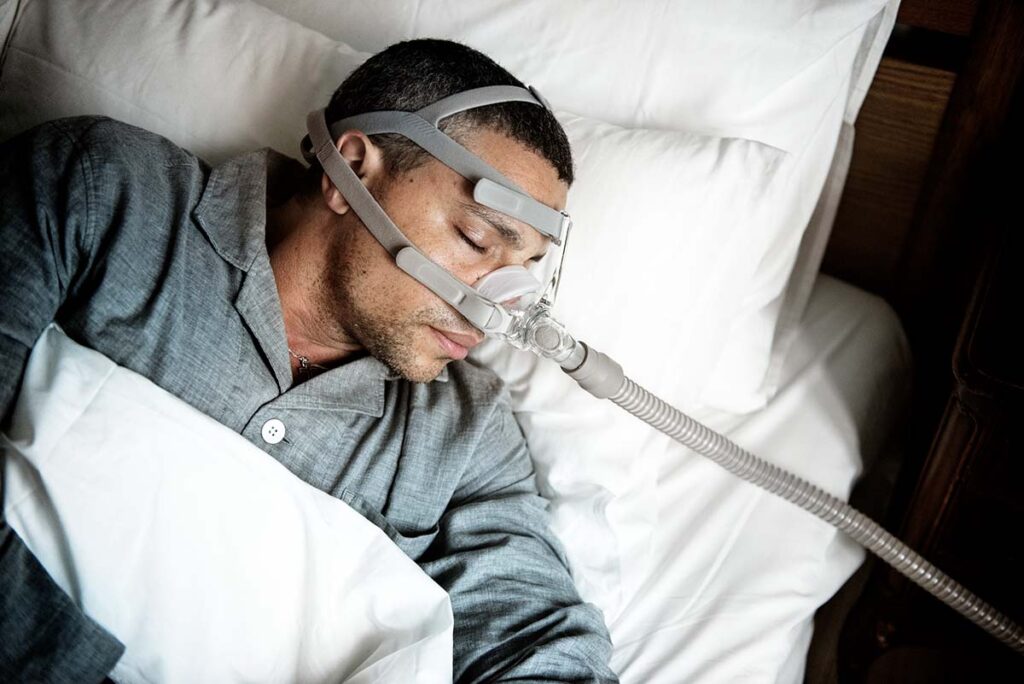 Man sleeping with CPAP instead of addressing his oral health with a great dentist.