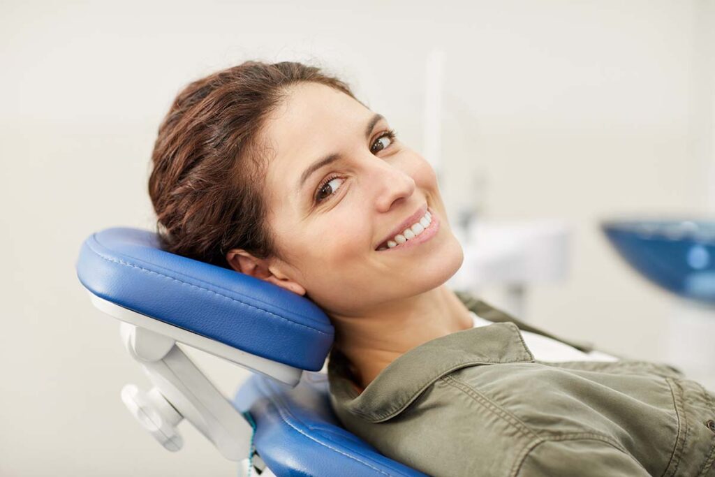 Woman smiling in the dental chair showing off her optimal dental health at the dental office.
